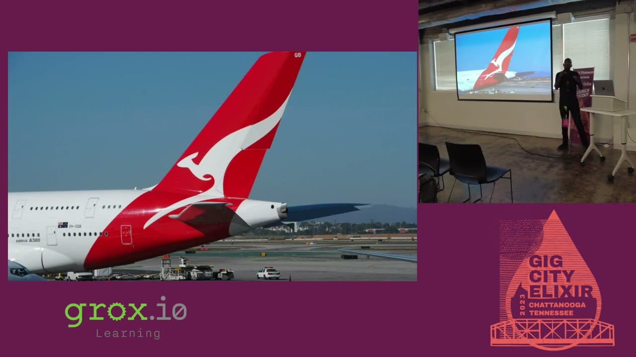 An aircraft slide on screen at GigCity Elixir 2023 with Sigu Magwa presenting beside it